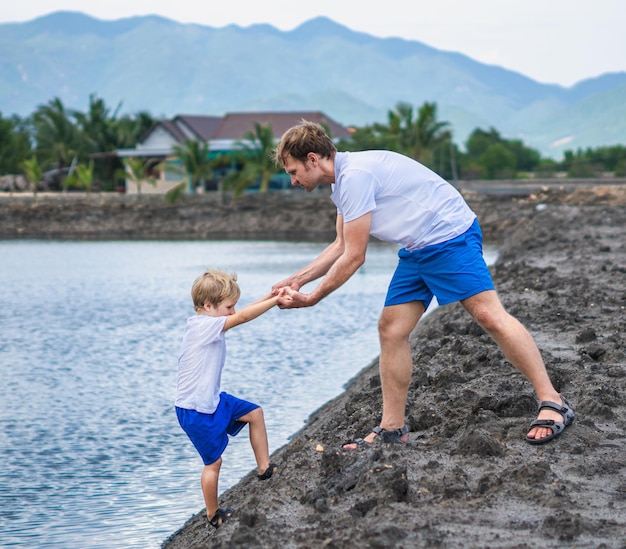 Papa hilft dem Sohn, zum Wasser des Sees zu gehen, erklärt die Sicherheitsregeln