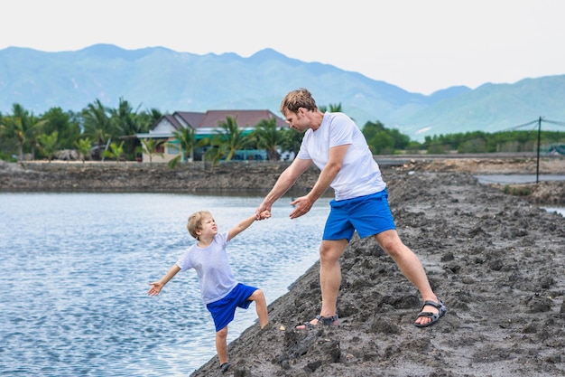 Papa hilft dem Sohn, zum Wasser des Sees zu gehen, erklärt die Sicherheitsregeln