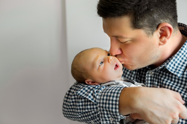 Foto papá joven guapo con un hijo pequeño en casa