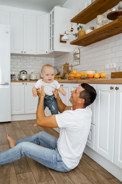 papá juega con el bebé en el piso de la cocina