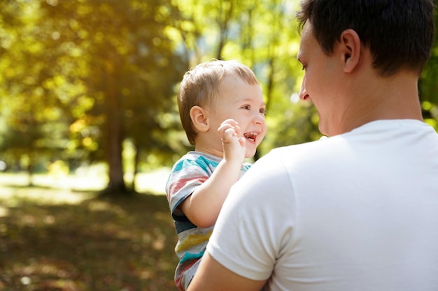 Papá juega con su hijo pequeño en el jardín al aire libre Tiempo en familia Feliz gente sonriente Niño de un año y medio Niño pequeño Enfoque selectivo