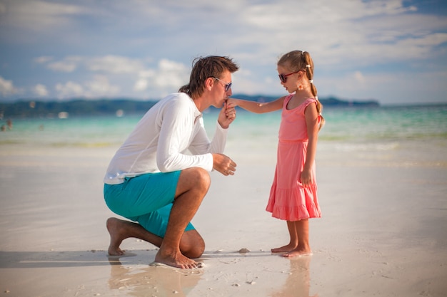 Papa küsst die Hand seiner kleinen Tochter am exotischen Strand
