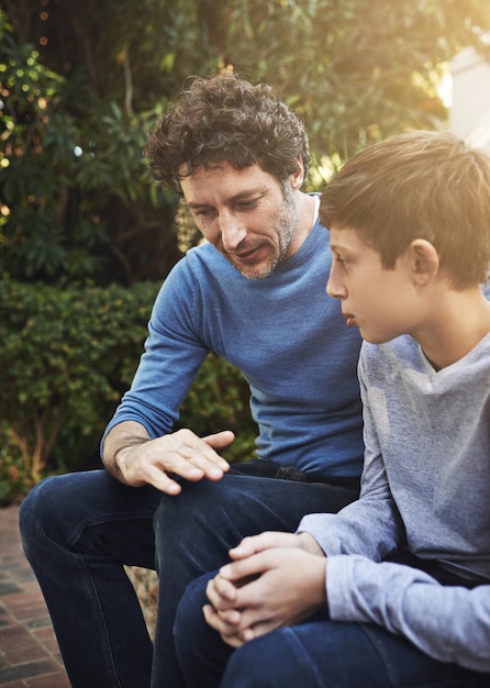 Papá lo sabe mejor Toma de un padre y su hijo conversando sinceramente en el patio trasero