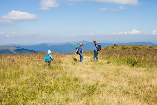 Papá, mamá e hijo con mochilas viajan por las montañas