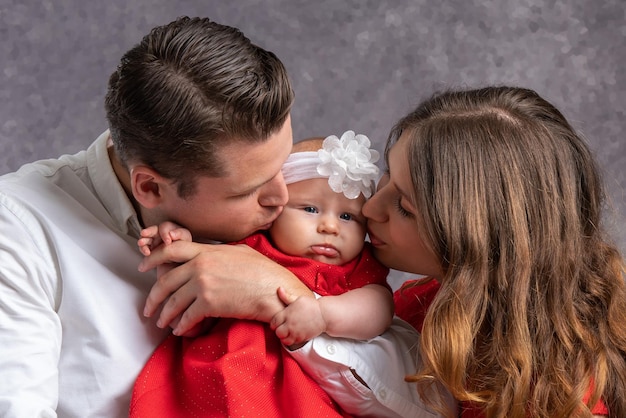 Papá y mamá jóvenes besan tiernamente a su niña Amor y ternura de los padres Retrato Primer plano