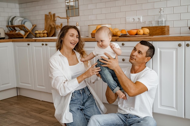 papá y mamá jugando con el bebé en el piso de la cocina