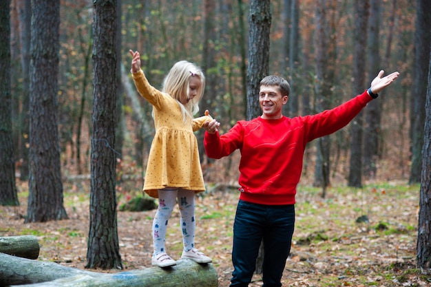 Papá y mamá con su hija caminan en otoño en el bosque Familia en la naturaleza