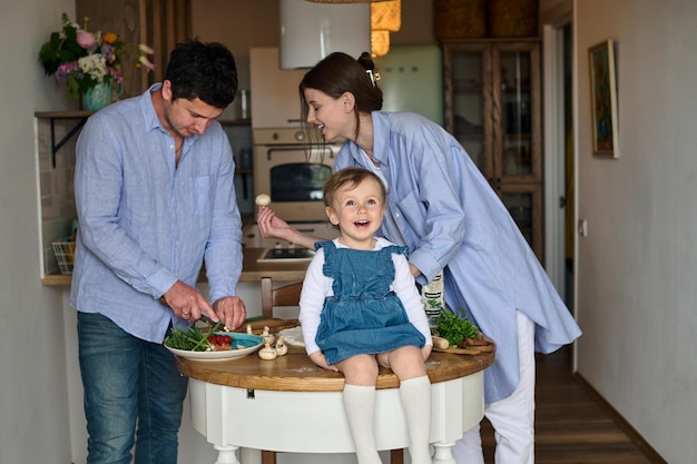 Papá mamá y su hija cocinan pizza juntos en la cocina El concepto de una familia feliz