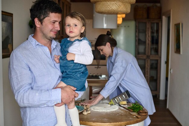 Papa Mama und ihre Tochter kochen Pizza zusammen in der Küche Das Konzept einer glücklichen Familie