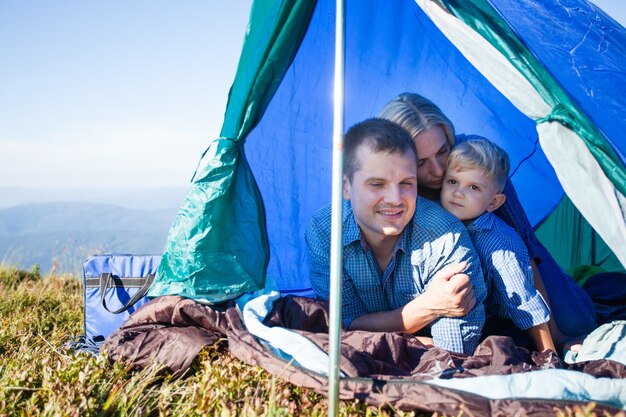 Papa, Mama und Sohn schauen aus dem Zelt, während sie in den Bergen unterwegs sind