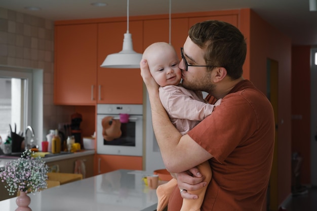 Papa mit Babymädchen in seinen Händen zu Hause kuscheln