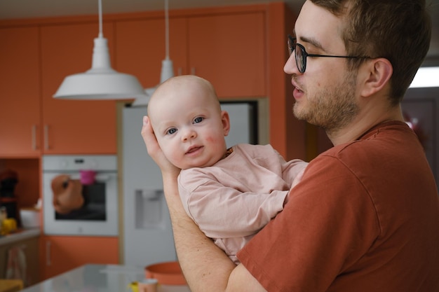 Papa mit Babymädchen in seinen Händen zu Hause kuscheln