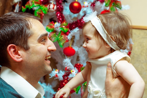 Papa mit seiner kleinen Tochter schaut sich zu Weihnachten in die Augen und lächelt. Weihnachtsstimmung. Neues Jahr.