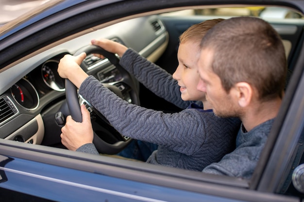 Papá le muestra a su pequeño hijo cómo conducir un automóvil