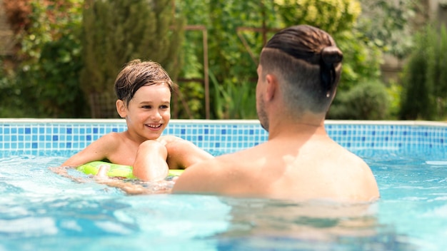 Papá nadando con su hijo feliz en la piscina