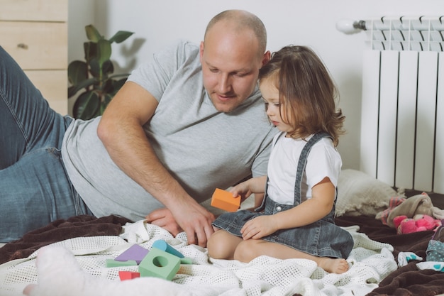 Papá y niña juegan con constructor sentado en el piso en casa