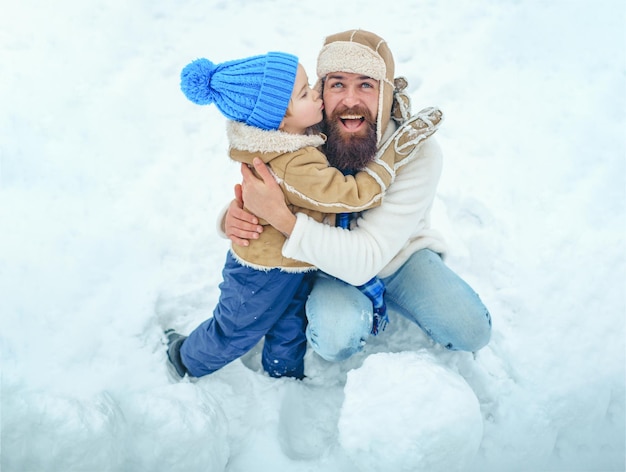 Papá y niño sonriendo y abrazando a padre e hijo haciendo muñeco de nieve retrato de invierno de papá e hijo en ...