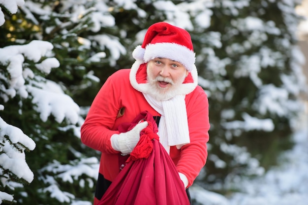 Papá Noel con una bolsa de regalos camina en las montañas nevadas de invierno nieve en Navidad
