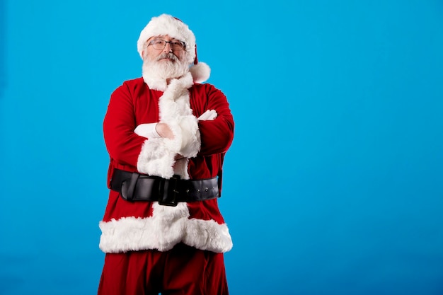 Papá Noel con los brazos cruzados sobre un fondo azul.