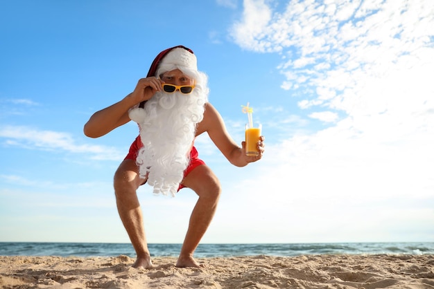 Foto papá noel con cóctel en la playa espacio para texto vacaciones de navidad