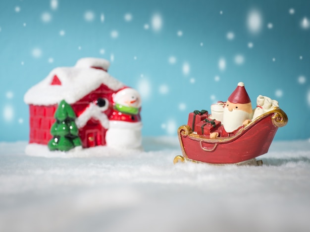 Papá Noel feliz con la caja de regalos en el trineo de la nieve que va a nevar casa.