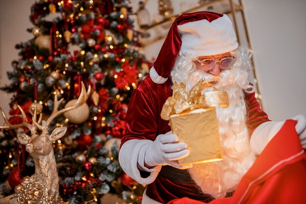 Papá Noel con una gran bolsa roja de regalos se apresura a llevar presente a los niños. Año nuevo y feliz Navidad, felices fiestas concepto