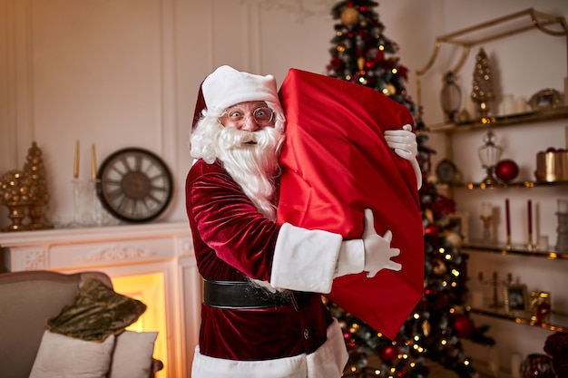 Papá Noel con una gran bolsa roja de regalos se apresura a llevar presente a los niños.