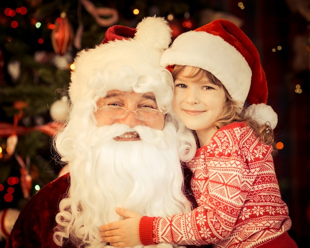 Papá Noel y niño en casa contra el árbol de Navidad. Concepto de vacaciones en familia.