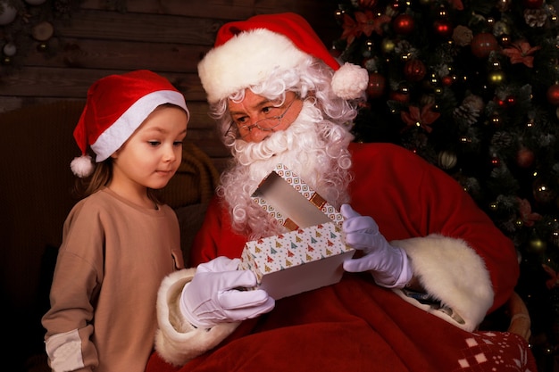 Papá Noel y niño en casa. Regalo de Navidad. Concepto de vacaciones en familia.