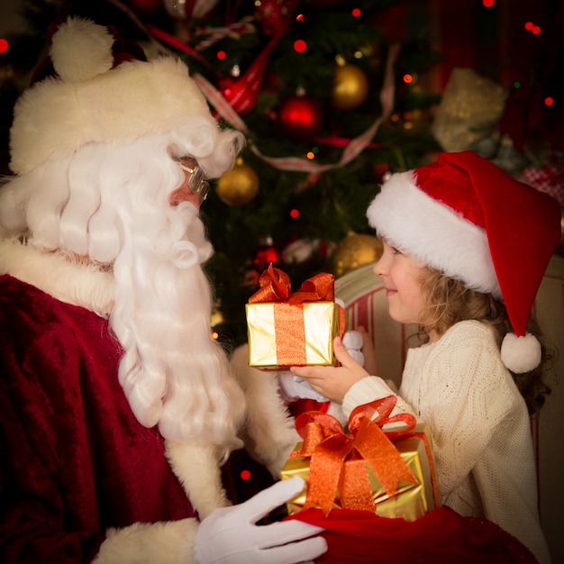 Papá Noel y niño en casa. Regalo de Navidad. Concepto de vacaciones familiares