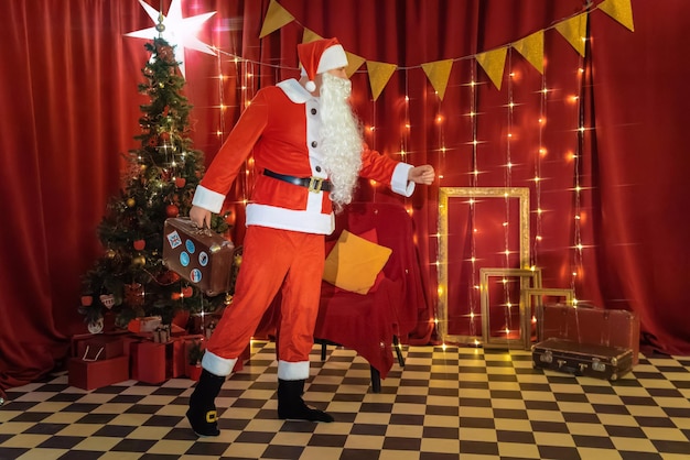 Foto papá noel de pie en una habitación con un árbol de navidad y regalos