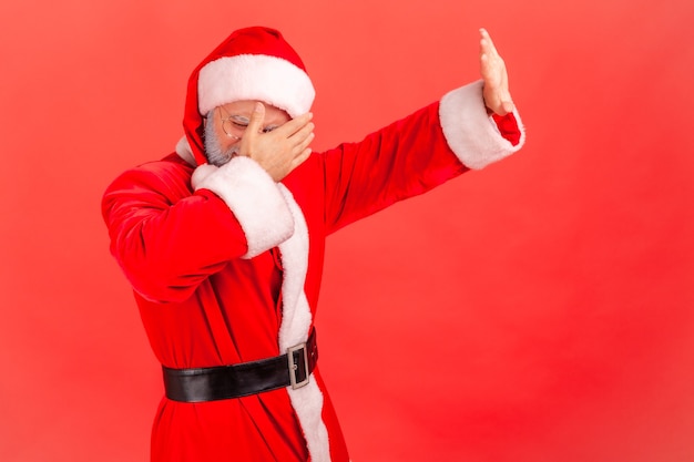 Papá Noel de pie, tapándose la cara y mostrando el gesto de parada con la mano.