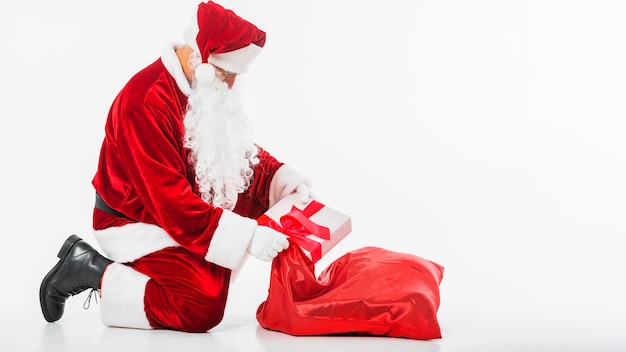 Foto papá noel poniendo caja de regalo en saco