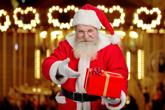 Papá Noel que muestra la caja con el presente.