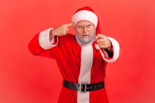 Papá Noel que muestra un gesto estúpido que le señala con el dedo mirando a la cámara, culpando y burlándose.