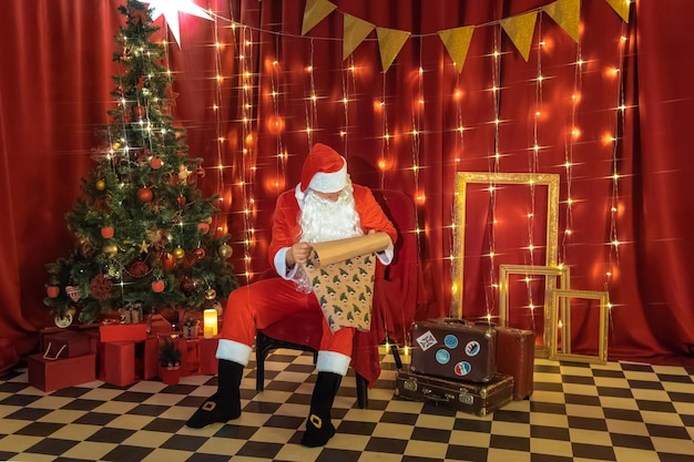 Foto papá noel con un regalo en las manos sobre el fondo del árbol de navidad