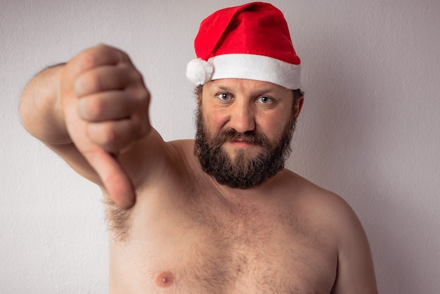 Papá Noel semidesnudo barbudo que muestra el pulgar hacia abajo gesto con una mano