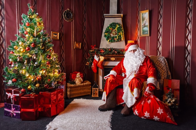 Foto papá noel sentado junto a un árbol de navidad