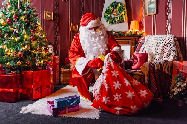 Foto papá noel sentado junto a un árbol de navidad