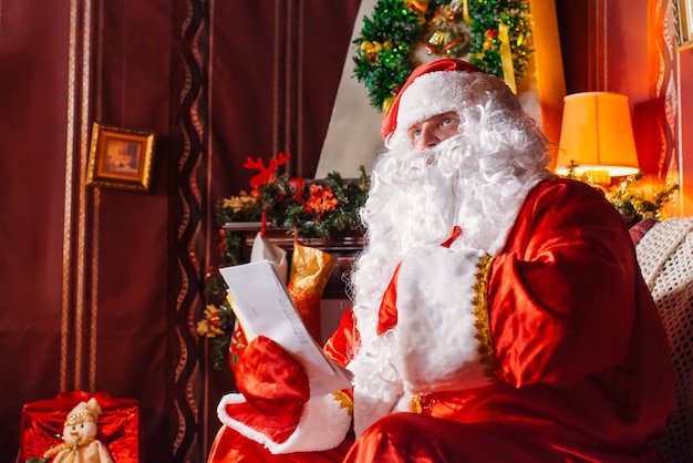 Foto papá noel sentado junto a un árbol de navidad