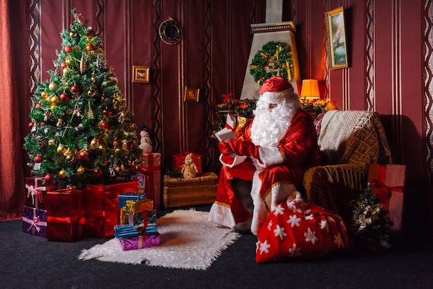 Papá Noel sentado junto a un árbol de Navidad