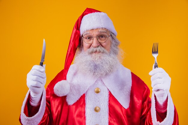 Papá Noel sosteniendo un cuchillo y un tenedor