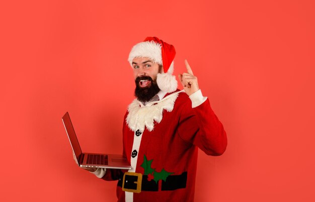 Foto papá noel usando la computadora portátil papá noel compras en línea con la computadora portátil comprar regalos de navidad en línea