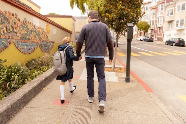 Foto papá paseando a su hijo el primer día de clases.