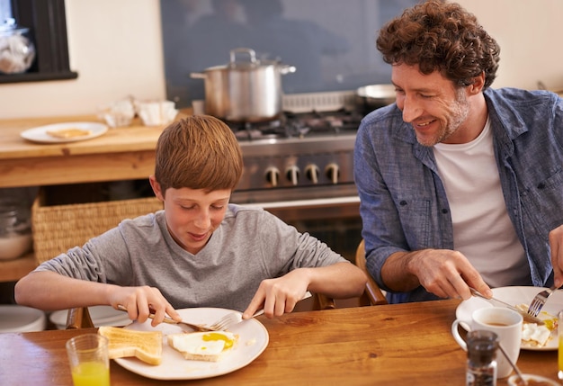 Papá prepara el mejor desayuno Captura recortada de un niño y su papá disfrutando del desayuno en la cocina de su casa