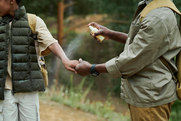 Papá protegiendo a su hijo de insectos usando spray durante su caminata en el bosque