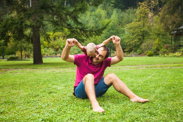 Papá se sentó en el césped y jugaba con su hijo en el parque.