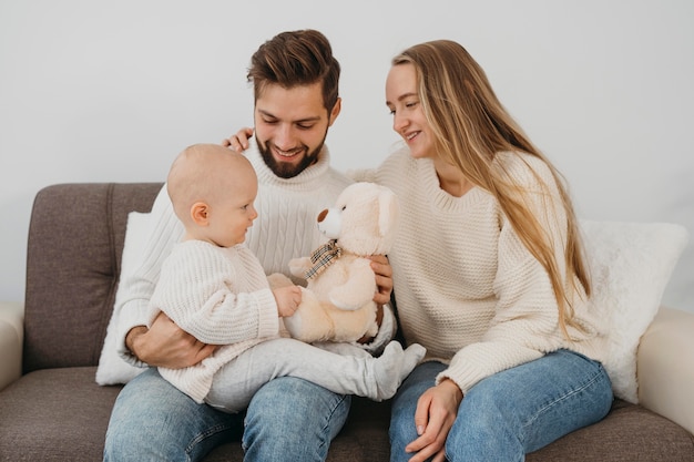 Papá sonriente y mamá con bebé en casa