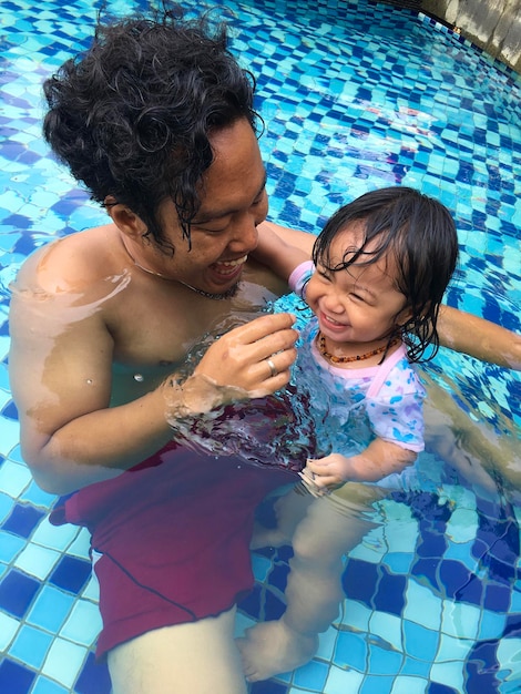 Foto papá con su hija nadando en la piscina