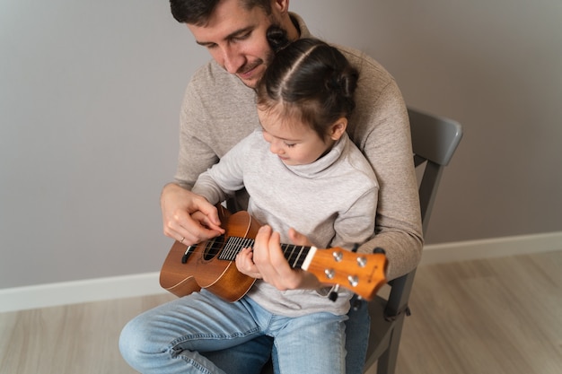 Papá toca la guitarra con su hija.